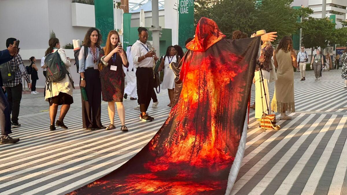 Carmen Capriles stood out at COP28 by wearing a blazing robe with a five-meter-long train picturing a forest in flames.